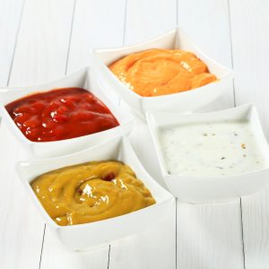 various salsa dips in white square bowls